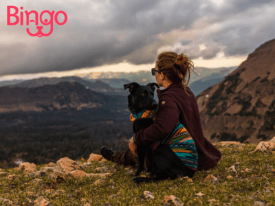 Bingo pet insurance review featuring a woman hugging a dog and enjoying a valley view